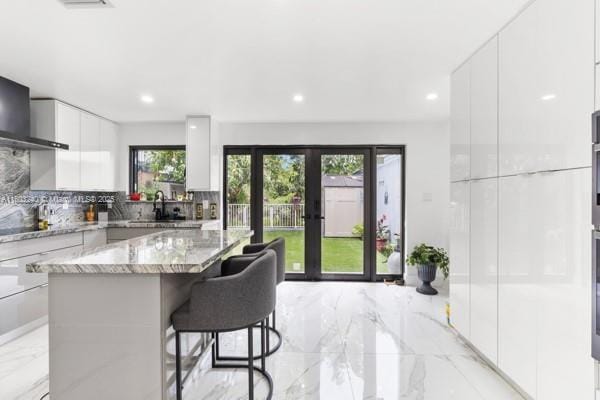 1594 W 73rd St, Hialeah, FL 33014 - kitchen featuring modern cabinets, light marble finish floors, light stone countertops, white cabinets, and a center island