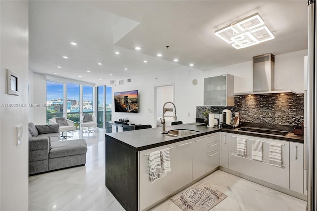 18201 Collins Ave Unit 808, Sunny Isles Beach, FL 33160 - kitchen with a sink, wall chimney range hood, black electric stovetop, decorative backsplash, and dark countertops