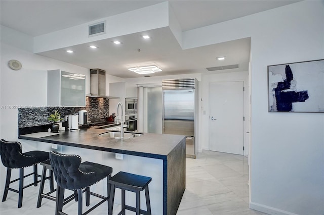 18201 Collins Ave Unit 808, Sunny Isles Beach, FL 33160 - kitchen featuring built in appliances, wall chimney exhaust hood, a peninsula, modern cabinets, and a breakfast bar area