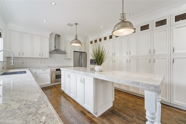 5860 La Gorce Dr, Miami Beach, FL 33140 - kitchen featuring stainless steel appliances, wall chimney exhaust hood, a sink, white cabinets, and backsplash