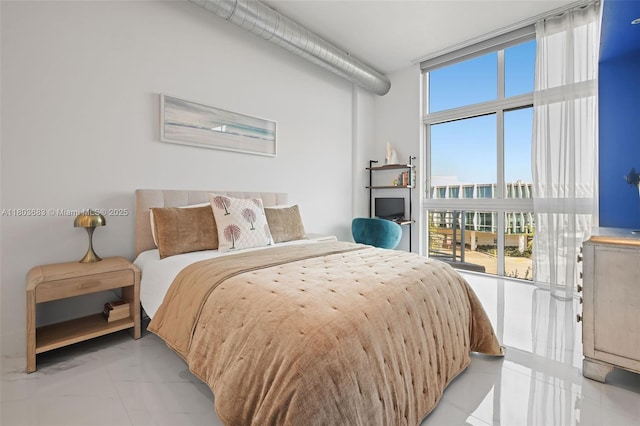 bedroom with expansive windows, access to exterior, and light marble finish flooring
