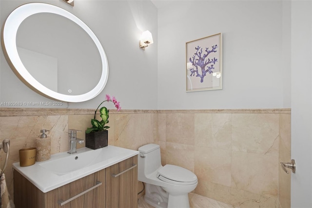 bathroom with tile walls, toilet, vanity, and wainscoting