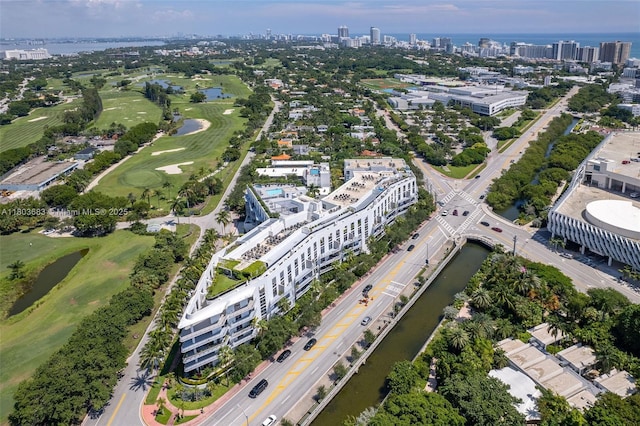 aerial view of property and surrounding area with a large body of water, a local golf course, and nearby urban area