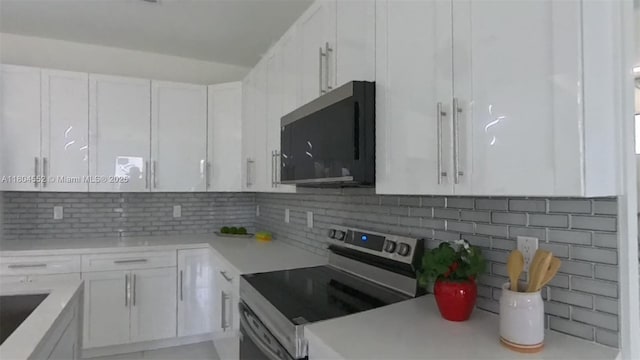 3004 SW 4th St, Lehigh Acres, FL 33976 - kitchen with electric stove, white cabinetry, decorative backsplash, and light countertops