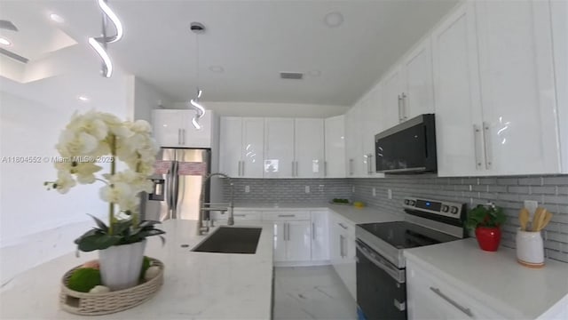 3004 SW 4th St, Lehigh Acres, FL 33976 - kitchen with appliances with stainless steel finishes, a sink, white cabinetry, light countertops, and decorative backsplash