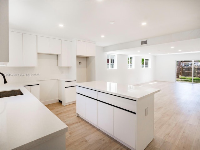 2039 NE 172nd St, North Miami Beach, FL 33162 - kitchen with a sink, a kitchen island, white cabinetry, light wood finished floors, and recessed lighting