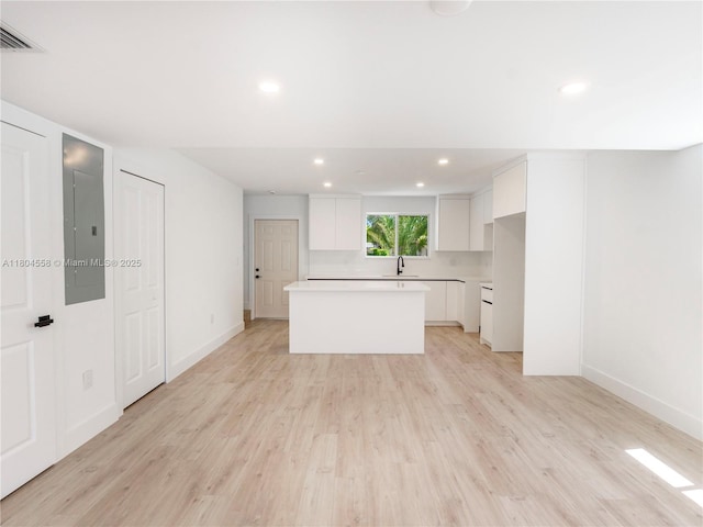 2039 NE 172nd St, North Miami Beach, FL 33162 - kitchen featuring a kitchen island, white cabinetry, a sink, light wood-style flooring, and recessed lighting
