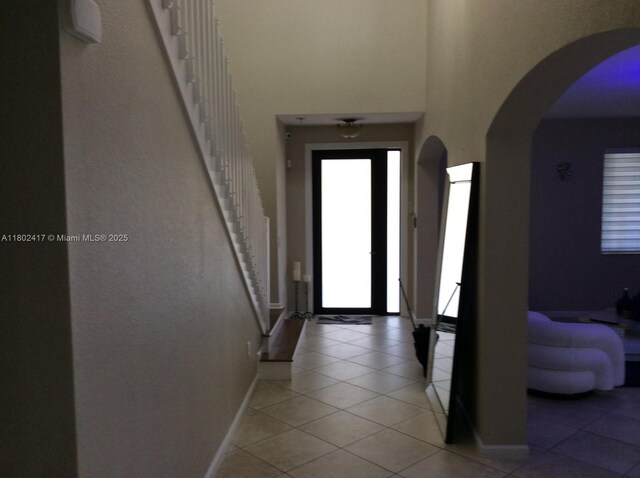 21046 SW 133rd Ct, Miami, FL 33177 - entryway featuring a towering ceiling, light tile patterned flooring, stairs, baseboards, and arched walkways
