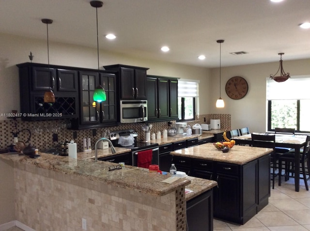 21046 SW 133rd Ct, Miami, FL 33177 - kitchen featuring stainless steel appliances, dark cabinetry, backsplash, a sink, and light stone counters