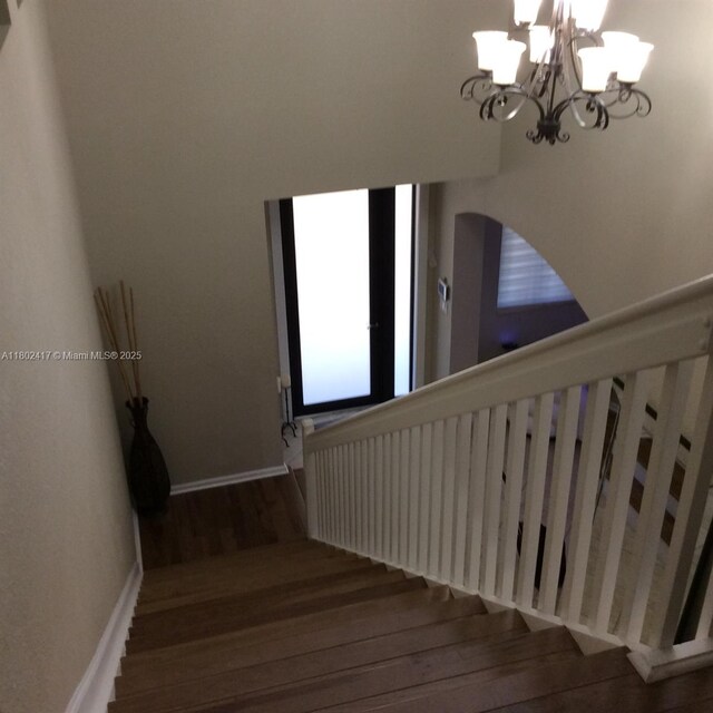21046 SW 133rd Ct, Miami, FL 33177 - staircase with wood finished floors, a chandelier, arched walkways, and baseboards