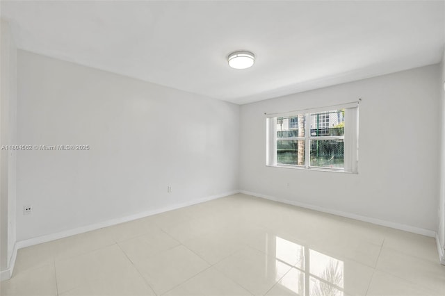 spare room featuring light tile patterned floors and baseboards