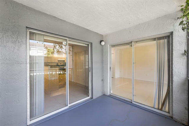exterior space featuring a textured wall, a textured ceiling, and finished concrete flooring