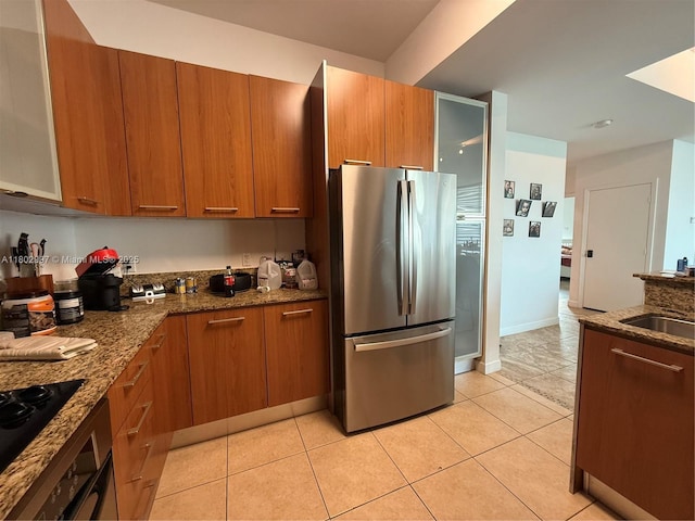 9066 SW 73rd Ct Unit 2401, Miami, FL 33156 - kitchen featuring freestanding refrigerator, dark stone counters, brown cabinetry, and a sink