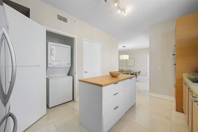 16275 Collins Ave Unit 1202, Sunny Isles Beach, FL 33160 - kitchen with stacked washer / dryer, freestanding refrigerator, modern cabinets, a kitchen island, and light tile patterned floors