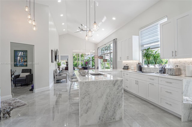 6670 NW 27th Ave, Boca Raton, FL 33496 - kitchen with a sink, a chandelier, decorative backsplash, light stone countertops, and high vaulted ceiling