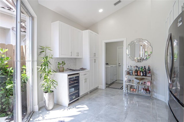 6670 NW 27th Ave, Boca Raton, FL 33496 - kitchen featuring beverage cooler, freestanding refrigerator, washing machine and clothes dryer, light countertops, and white cabinets
