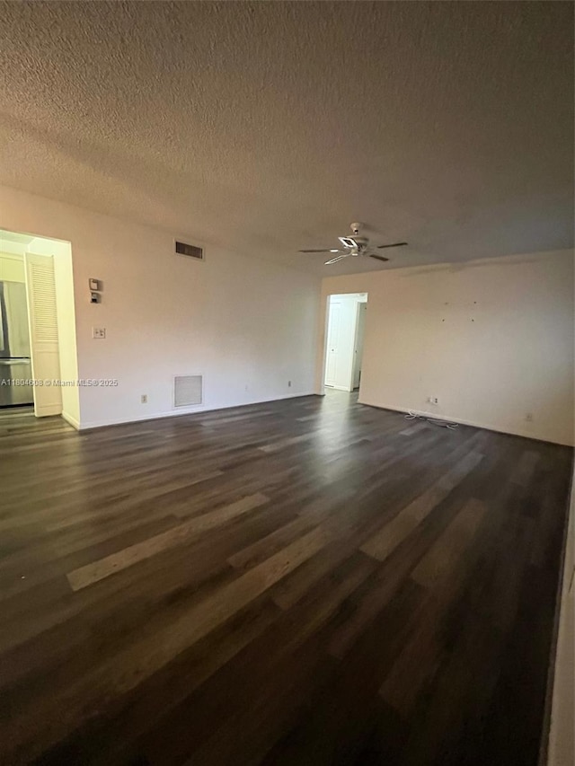 empty room featuring dark wood-type flooring, a ceiling fan, and a textured ceiling