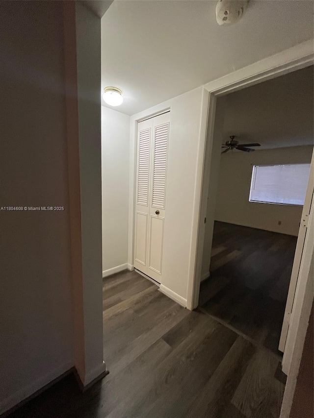 corridor featuring dark wood-style flooring and baseboards