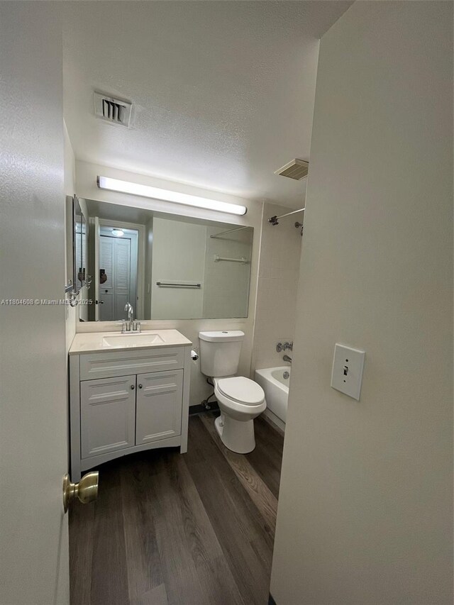 full bathroom featuring wood finished floors, vanity, toilet, shower / tub combination, and a textured ceiling