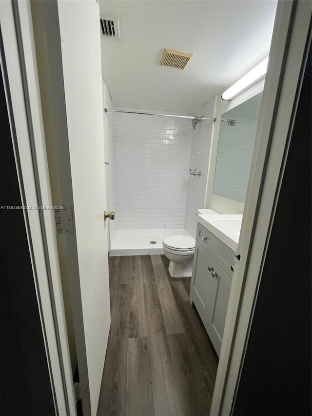 full bath featuring wood finished floors, a shower stall, vanity, and toilet