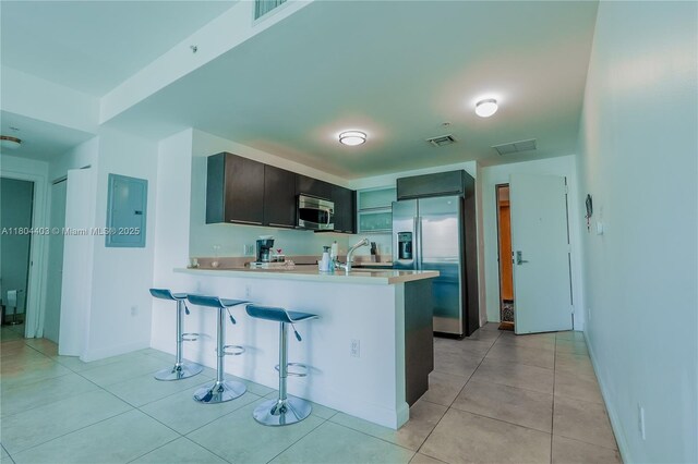 90 SW 3rd St Unit 1401, Miami, FL 33130 - kitchen featuring stainless steel appliances, a peninsula, a breakfast bar area, light countertops, and light tile patterned flooring