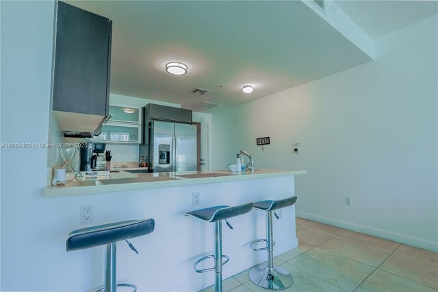 90 SW 3rd St Unit 1401, Miami, FL 33130 - kitchen featuring stainless steel fridge with ice dispenser, a peninsula, a kitchen bar, light countertops, and light tile patterned floors