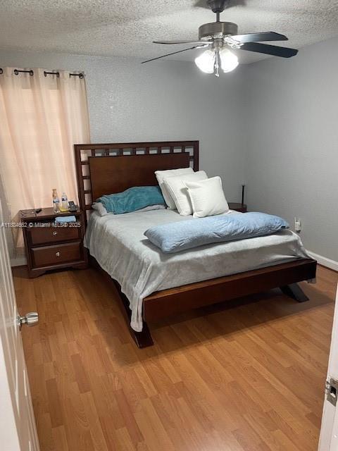 8340 NW 8th St Unit N12, Miami, FL 33126 - bedroom featuring wood finished floors, a textured ceiling, ceiling fan, and baseboards