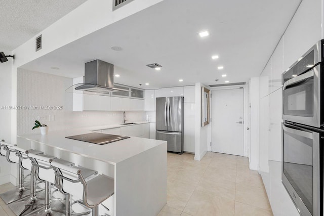 20355 NE 34th Ct Unit 929, Aventura, FL 33180 - kitchen featuring appliances with stainless steel finishes, exhaust hood, white cabinetry, a peninsula, and recessed lighting