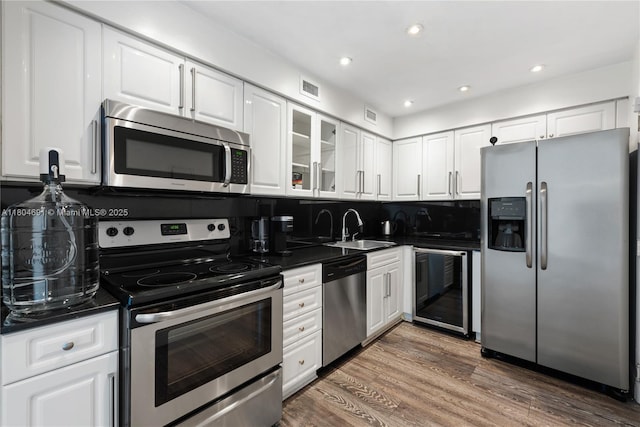 6770 Indian Creek Dr Unit Tsa1, Miami Beach, FL 33141 - kitchen featuring appliances with stainless steel finishes, wine cooler, a sink, dark countertops, and white cabinets