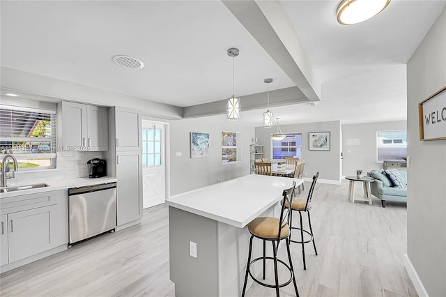 1950 NE 55th Ct, Fort Lauderdale, FL 33308 - kitchen with dishwasher, a sink, light wood-type flooring, a kitchen bar, and baseboards