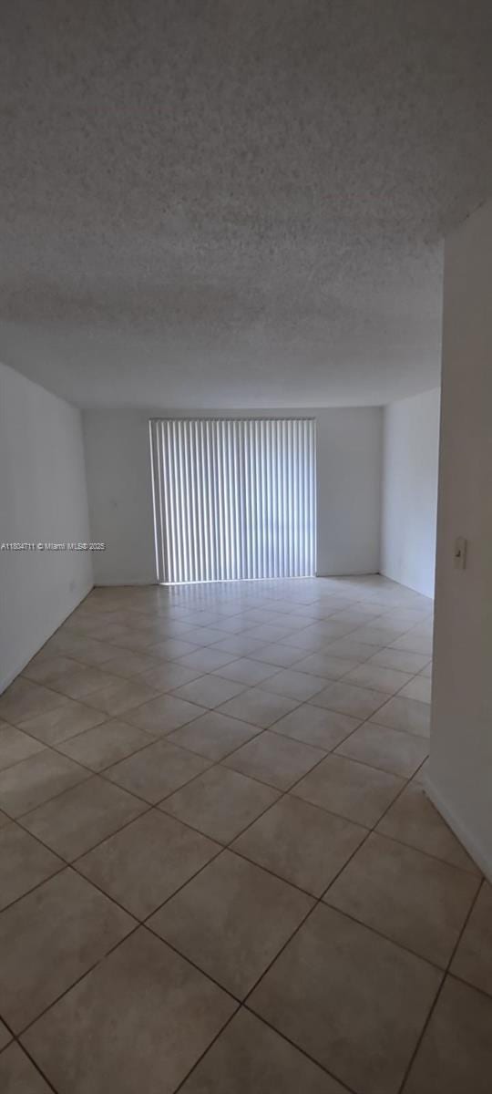 empty room featuring a textured ceiling and light tile patterned flooring
