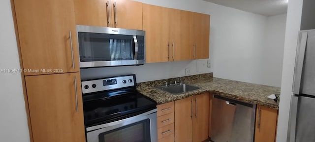kitchen featuring stainless steel appliances, a sink, and dark stone countertops