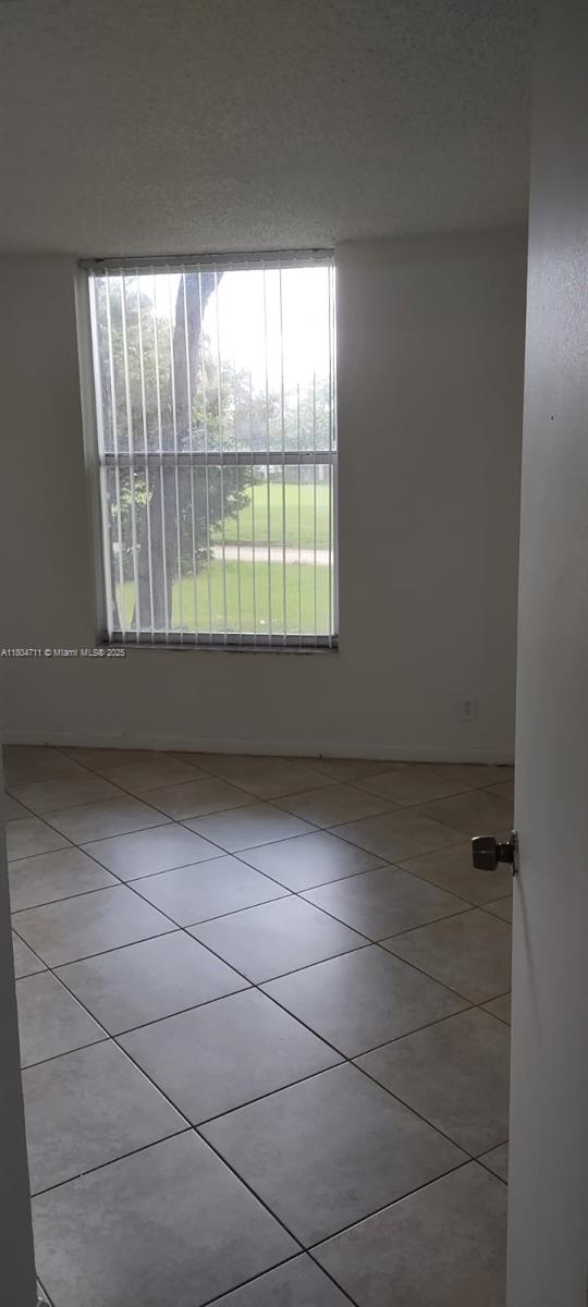 spare room with plenty of natural light and tile patterned floors
