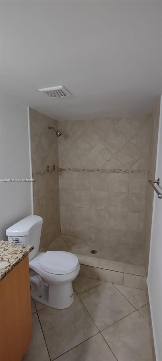 full bath featuring toilet, a shower stall, vanity, and tile patterned flooring