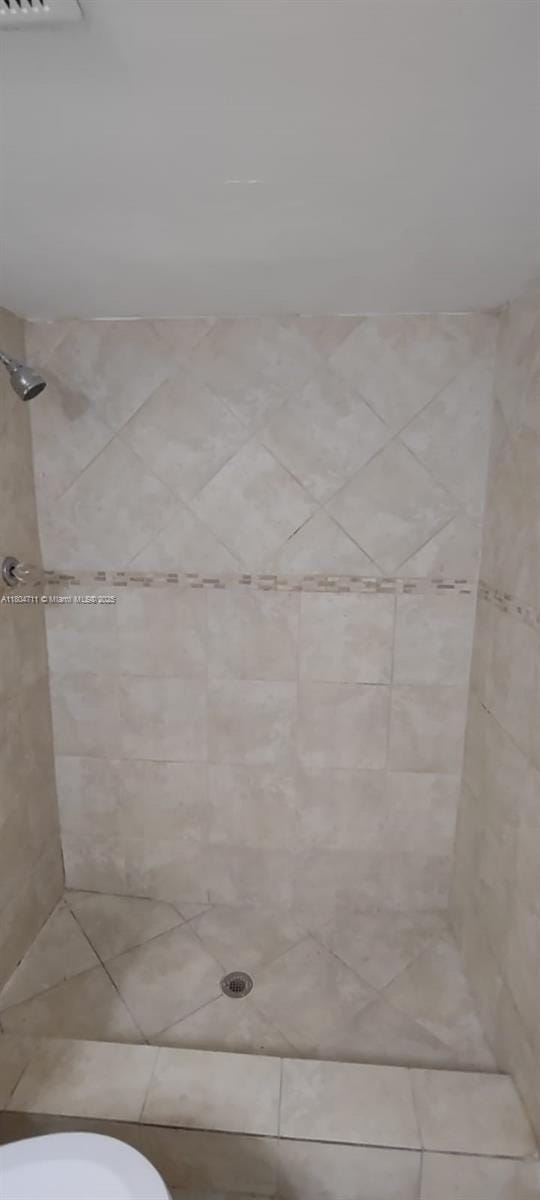 full bathroom featuring a tile shower and toilet
