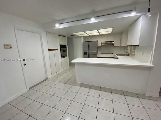 14953 SW 143rd Ct, Miami, FL 33186 - kitchen with stainless steel fridge, under cabinet range hood, a sink, a peninsula, and light countertops
