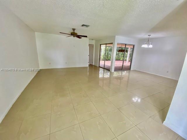 14953 SW 143rd Ct, Miami, FL 33186 - spare room with a chandelier, a textured ceiling, light tile patterned flooring, baseboards, and ceiling fan