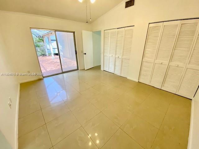 14953 SW 143rd Ct, Miami, FL 33186 - unfurnished bedroom featuring access to outside, vaulted ceiling, tile patterned flooring, multiple closets, and baseboards