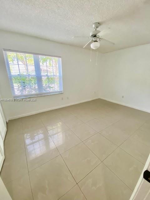 14953 SW 143rd Ct, Miami, FL 33186 - empty room with light tile patterned floors, baseboards, a textured ceiling, and ceiling fan