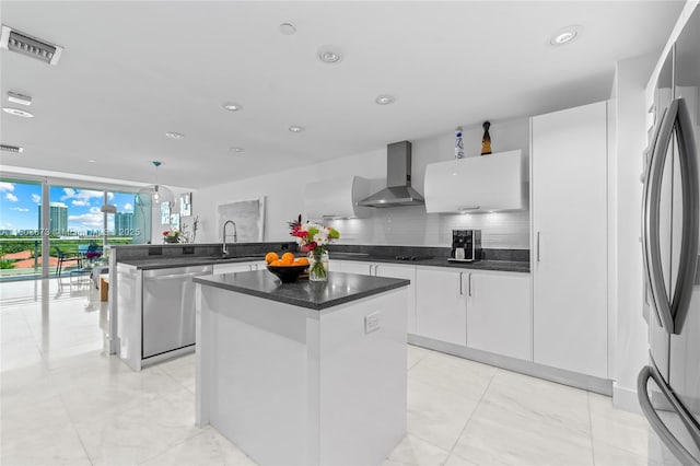 2950 NE 188th St Unit 540, Aventura, FL 33180 - kitchen with wall chimney exhaust hood, appliances with stainless steel finishes, a peninsula, a kitchen island, and white cabinetry