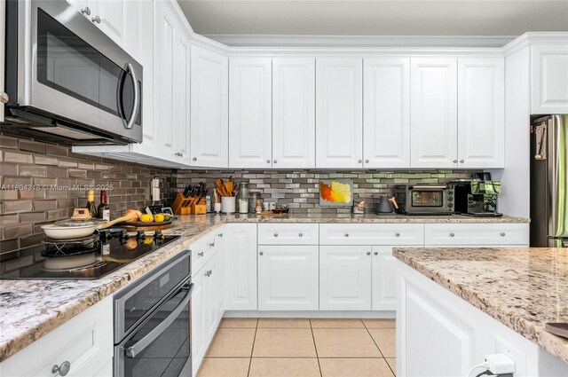 2626 Sawyer Ter, Wellington, FL 33414 - kitchen featuring stainless steel appliances, white cabinetry, light tile patterned floors, tasteful backsplash, and light stone counters