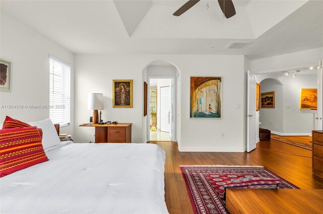 2626 Sawyer Ter, Wellington, FL 33414 - bedroom featuring arched walkways, hardwood / wood-style floors, rail lighting, and baseboards