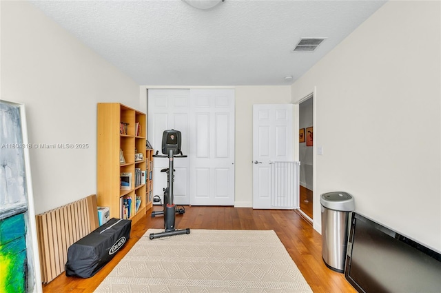 2626 Sawyer Ter, Wellington, FL 33414 - workout room with wood finished floors, a textured ceiling, radiator heating unit, and baseboards
