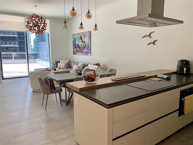 1000 Brickell Plz Unit 1805, Miami, FL 33131 - kitchen featuring wall chimney range hood, dark countertops, white cabinets, decorative light fixtures, and a chandelier