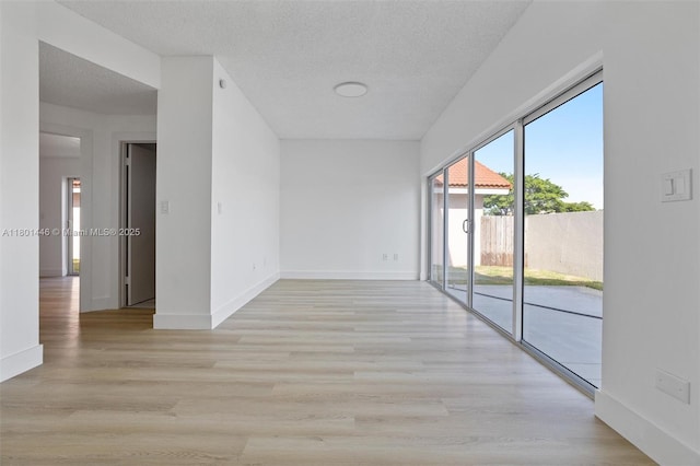8501 NW 191st St, Hialeah, FL 33015 - empty room with baseboards, a textured ceiling, and light wood-style flooring