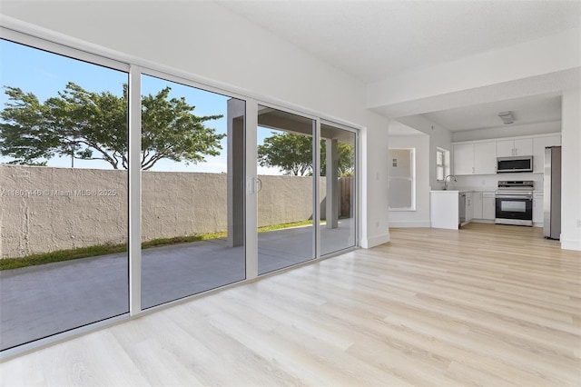 8501 NW 191st St, Hialeah, FL 33015 - unfurnished living room with light wood-style floors, a sink, and baseboards