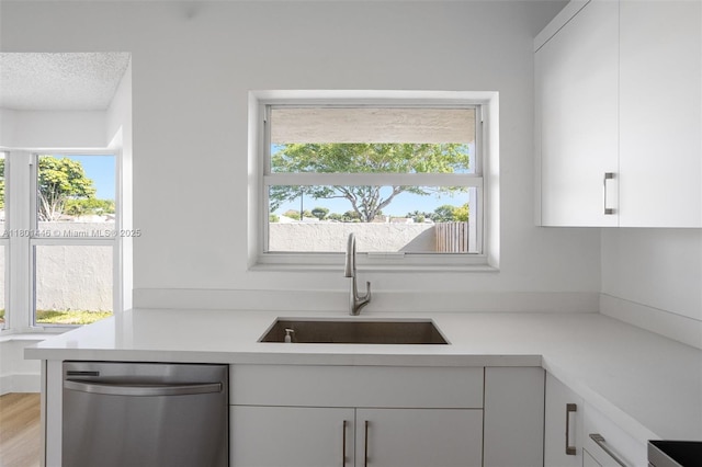 8501 NW 191st St, Hialeah, FL 33015 - kitchen with stainless steel dishwasher, a sink, light countertops, white cabinets, and a textured ceiling