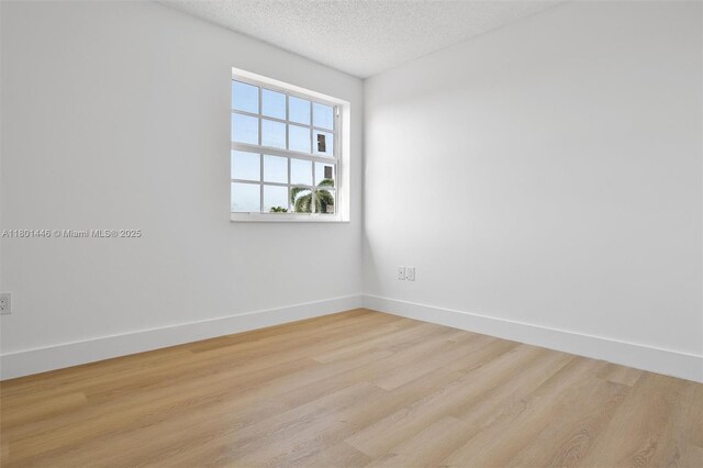 8501 NW 191st St, Hialeah, FL 33015 - spare room featuring light wood-style floors, baseboards, and a textured ceiling