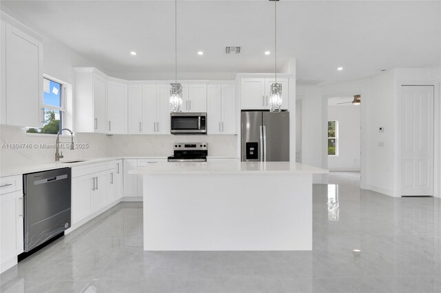 935 Elgin St, Lehigh Acres, FL 33974 - kitchen with stainless steel appliances, a sink, a center island, backsplash, and white cabinets
