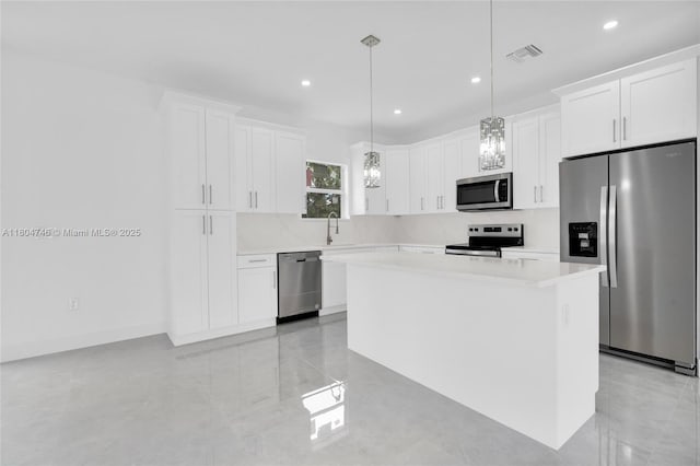 935 Elgin St, Lehigh Acres, FL 33974 - kitchen with stainless steel appliances, a center island, light countertops, white cabinets, and recessed lighting